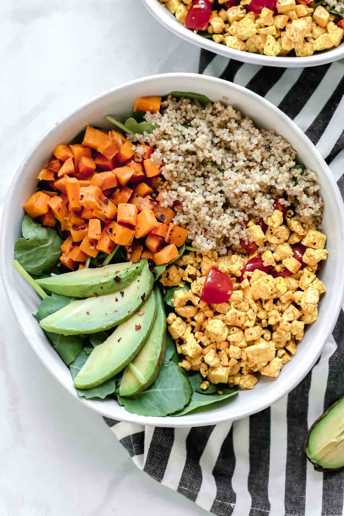 Colorful high-protein vegan tofu scramble bowl with hemp seeds and avocado on wooden table for weight loss