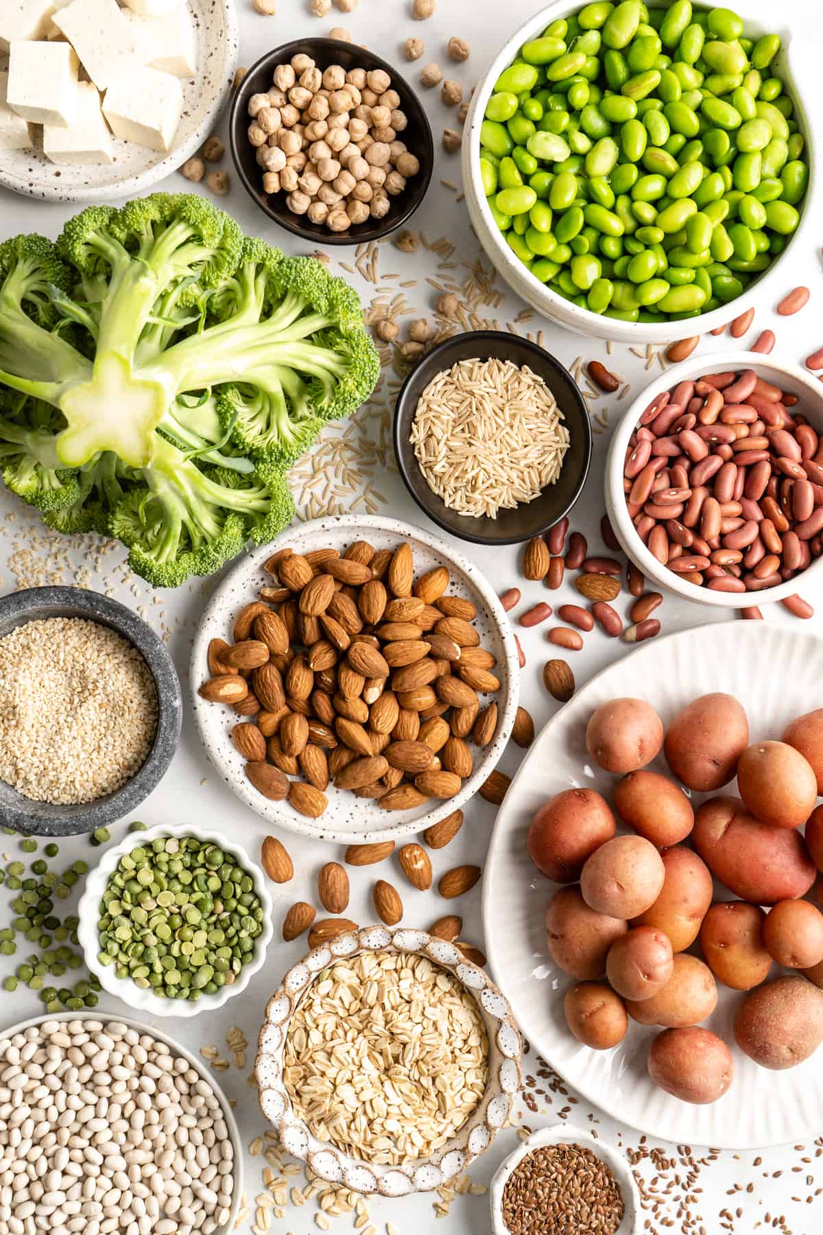 Colorful array of high-protein vegan ingredients including legumes, nuts, seeds, and grains on wooden cutting board